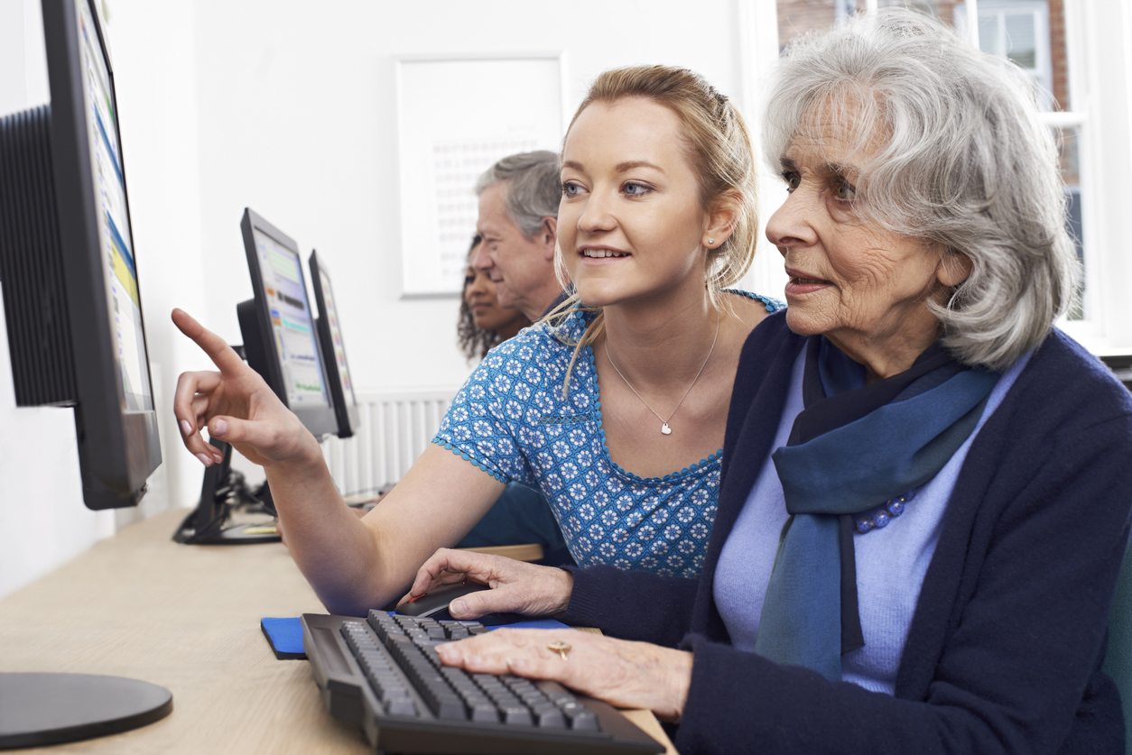 Woman helping senior use a computer at the library