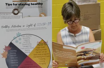 Photo of COVID-19 fact sheets with info about staying healthy during the pandemic, and a photo of a woman reading the fact sheets