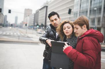 Three people in a city looking at a tablet