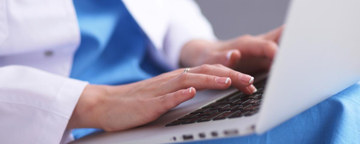 healthcare worker typing on a laptop