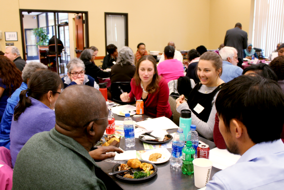 Researcher Tetyana Shippee talks with a group seated at a table during a community forum