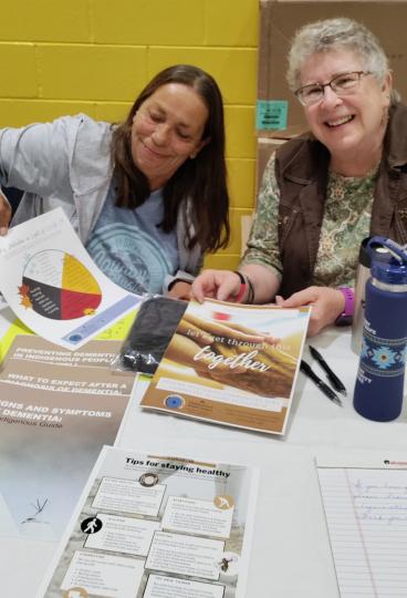 Shirley Stevens and Patricia Winchell-Dahl hand out the COVID-19 fact sheets at the Grand Portage Health Fair. Both are members of the Grand Portage ICARE Community Advisory group, who worked with UMN researchers to create the fact sheets.